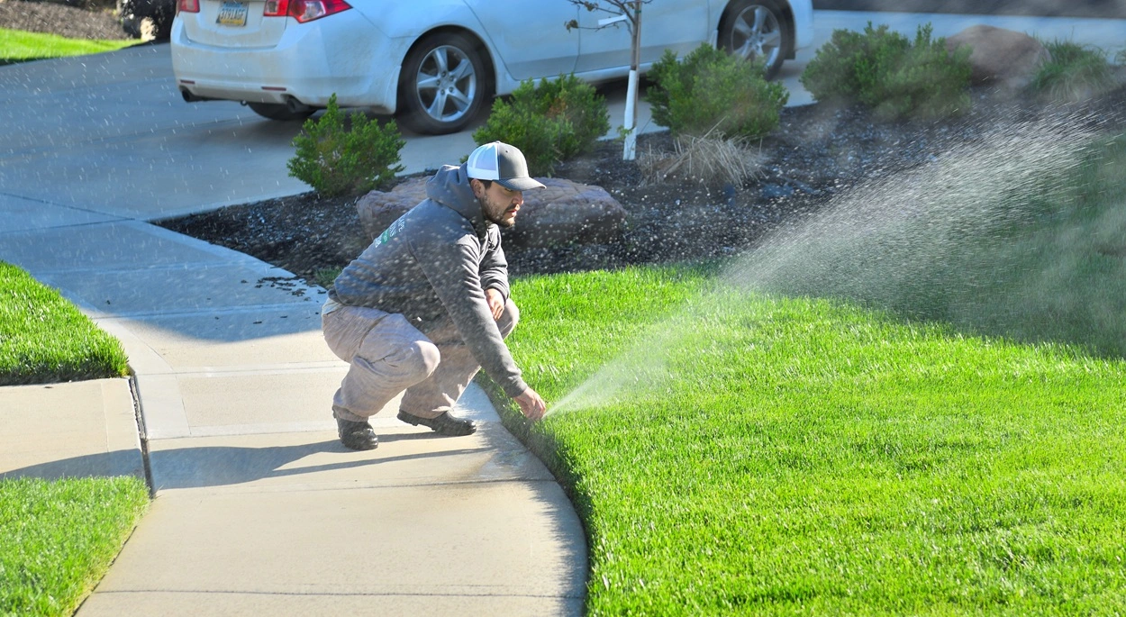 Irrigation repair expert fixing a broken sprinkler head near Leawood, KS.