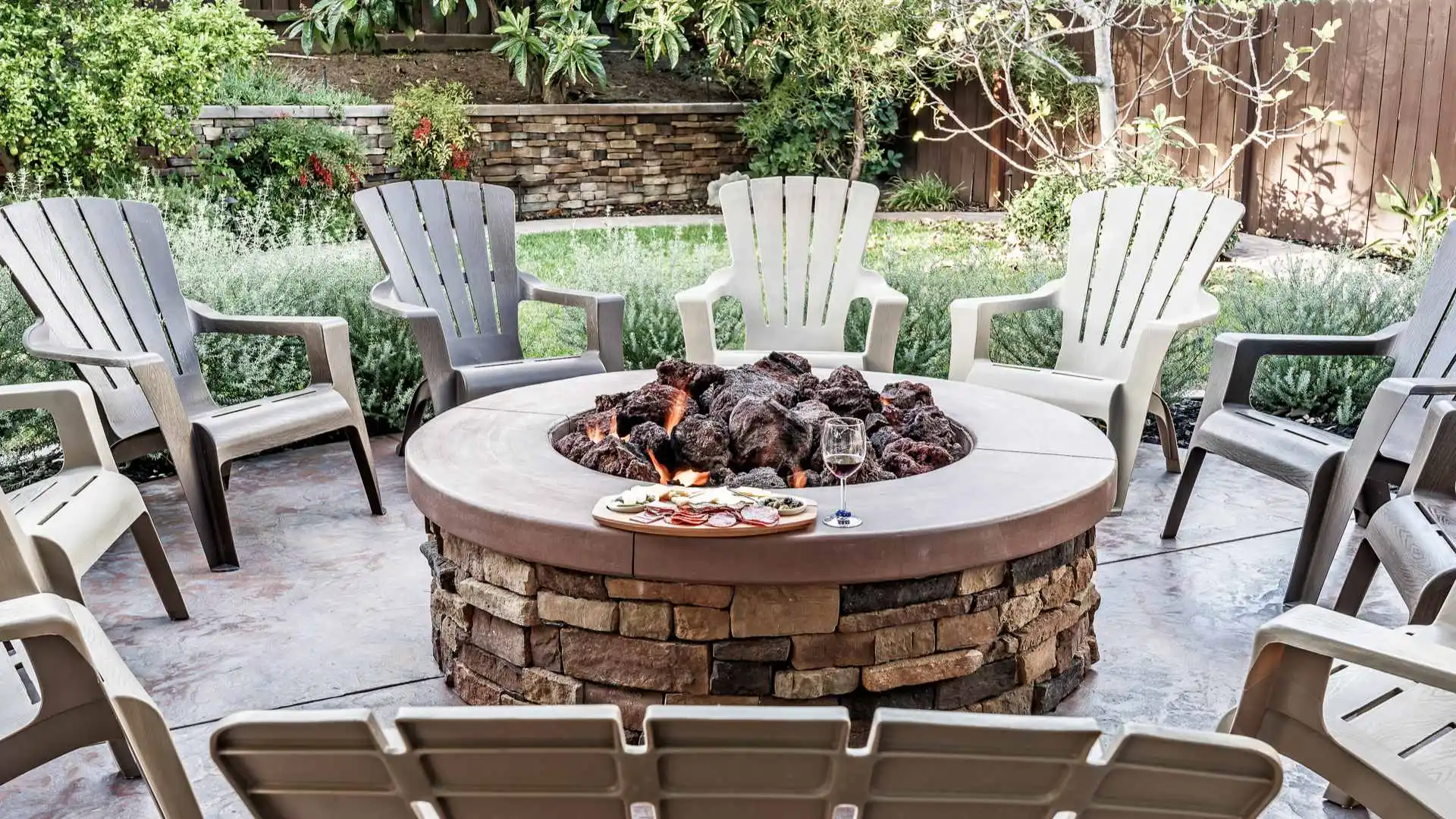 Fire pit with a tray of food and a glass of wine.