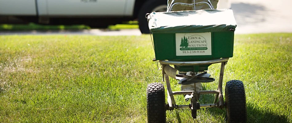 Green fertilizer spreader with a company logo in Overland Park, KS.