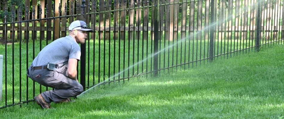 Irrigation professional in Overland Park, KS, checking a irrigation sprinkler head on a lawn.