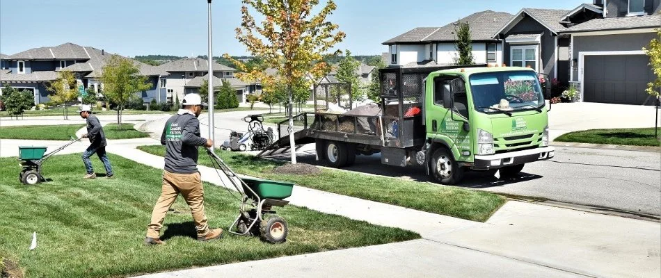 Two lawn care employees spreading fertilizer on a lawn in Overland Park, KS.