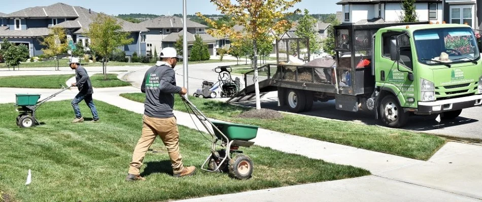 Men in Overland Park, KS, fertilizing a lawn.