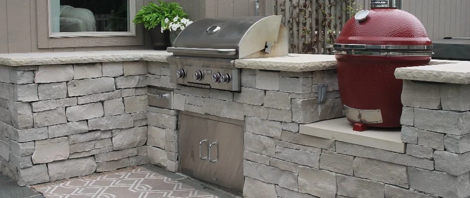 Outdoor kitchen in Overland Park, KS, with grill and red smoker.