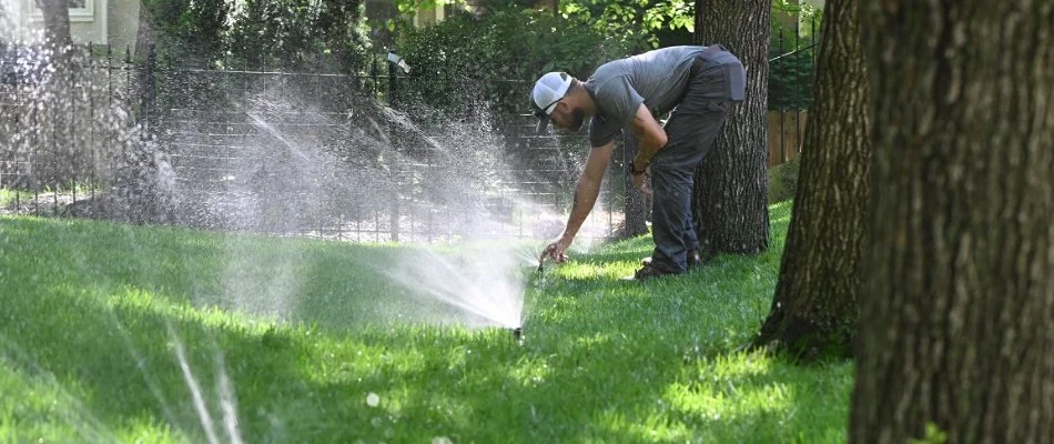 Technician adjusting lawn irrigation system in Overland Park, KS.