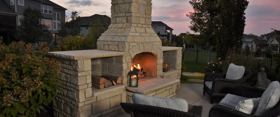 Large outdoor fireplace with three chairs in front of it on a property in Overland Park, KS.