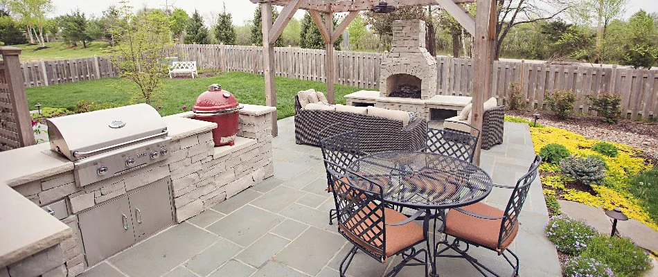 Outdoor living space with patio, outdoor kitchen, fireplace, and table in Winnebago, MO.
