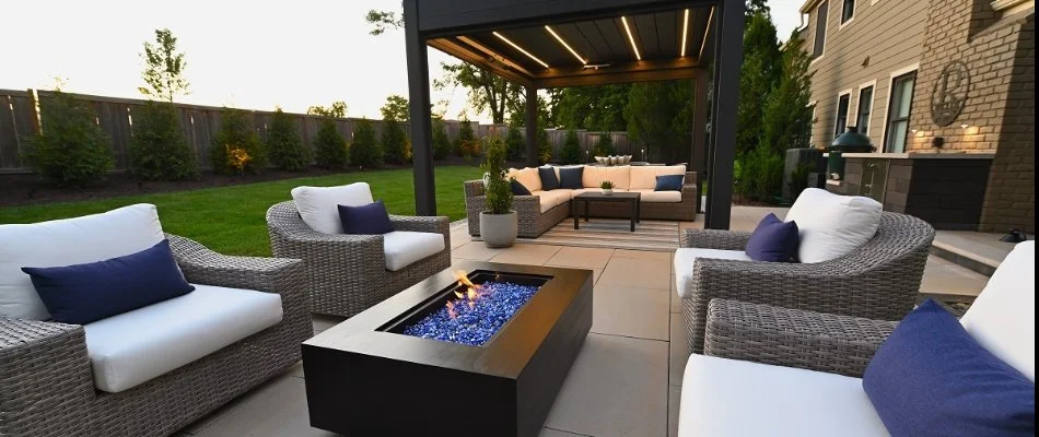 A paver patio in Overland Park, KS, with a black fire pit and pergola.