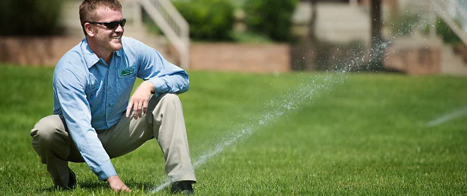 Professional adjusting a sprinkler head on a lawn in Overland Park, KS