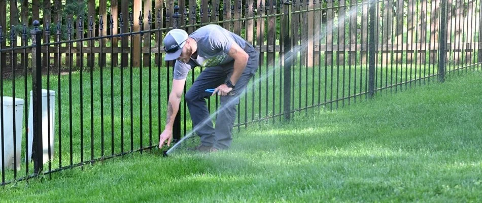 Tech adjusting a sprinkler head on a lawn in Belton, MO.