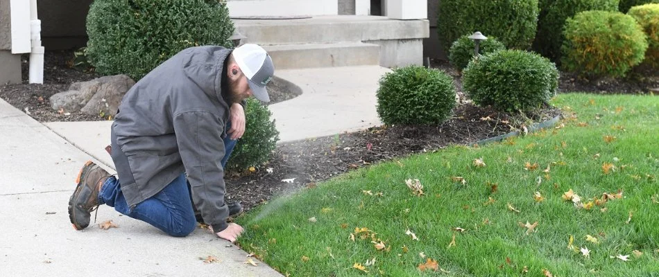 Technician adjuting a sprinkler head on a lawn in Cleveland, MO.