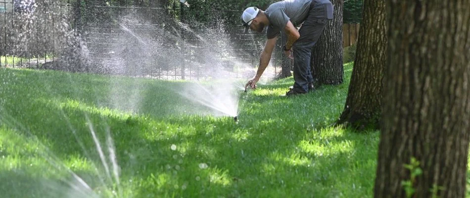 Worker adjusting sprinkler heads on a lawn in Spring Hill, KS.