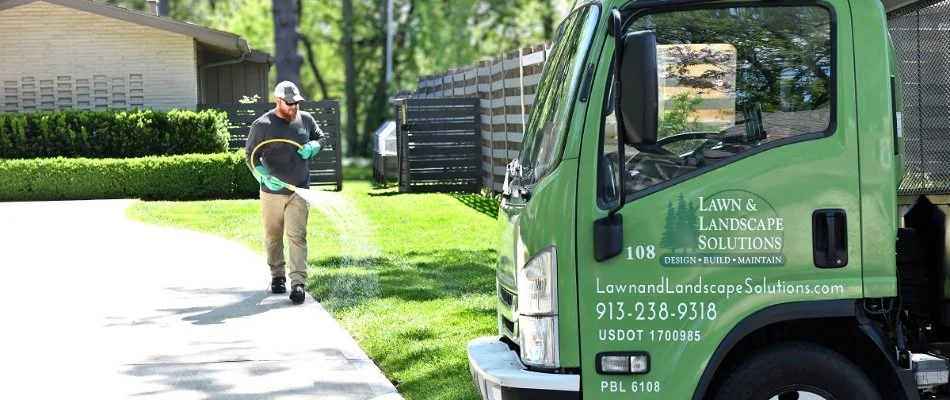 Worker applying a fertilizer treatment to a lawn in Overland Park, KS.