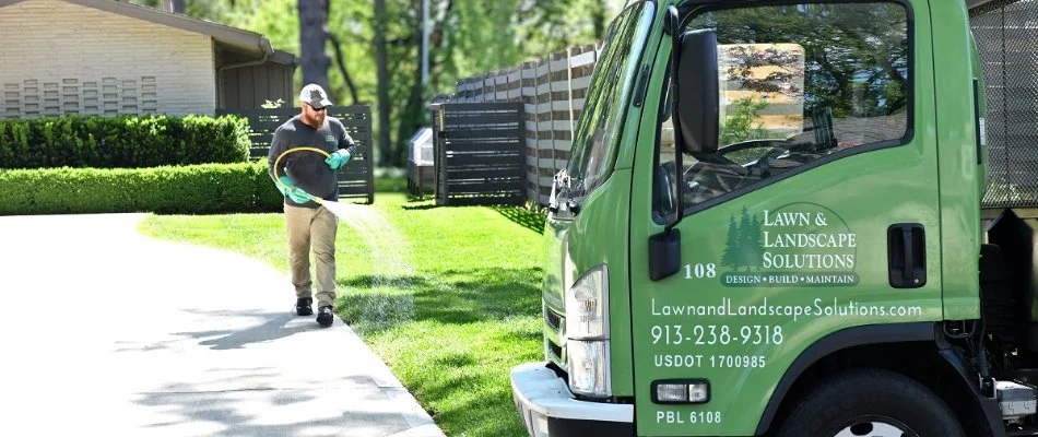 Worker applying liquid fertilizer treatment to a lawn in Overland Park, KS.