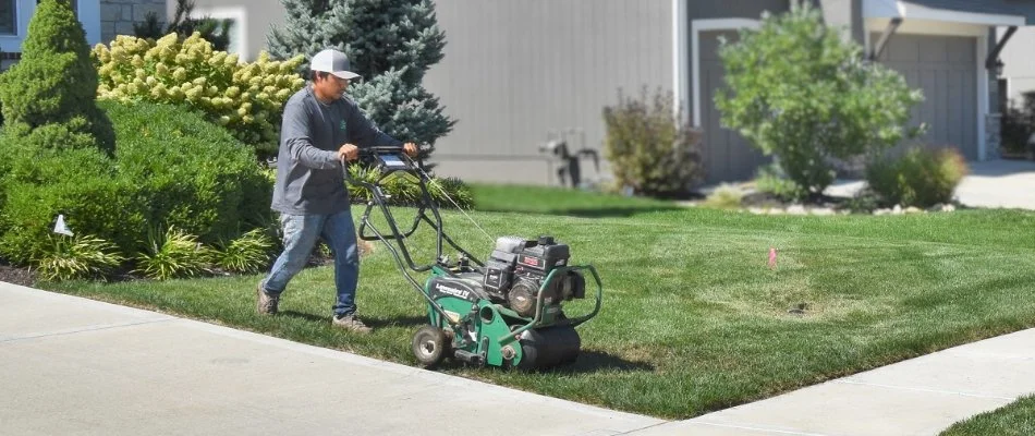 Worker pushing equipment across a lawn in Belton, MO.